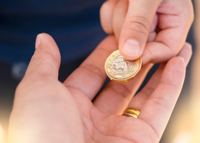 Someone passing a £1 coin to another person. 