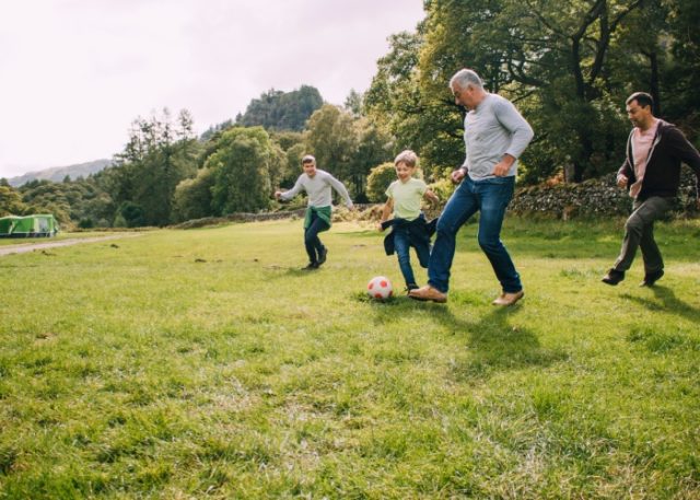 Multi-generational family playing football in a park.