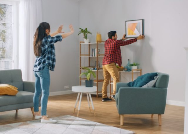 A couple hanging a picture in their new home.