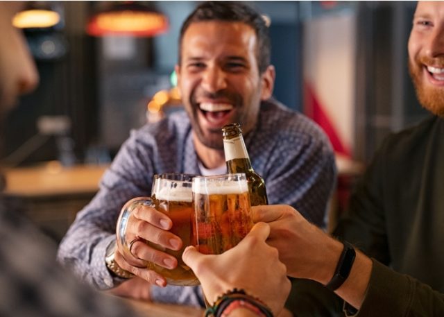 A group of friends clinking beer glasses in a pub.