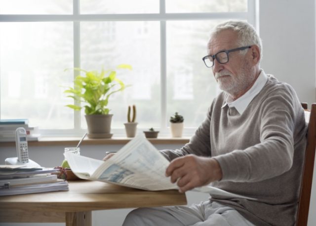 A man reading a newsletter at home.