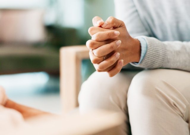 A woman sitting with her hands clasped.
