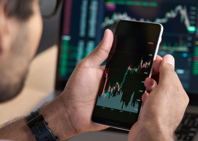 A man looking at a graph showing stock market performance on his phone.