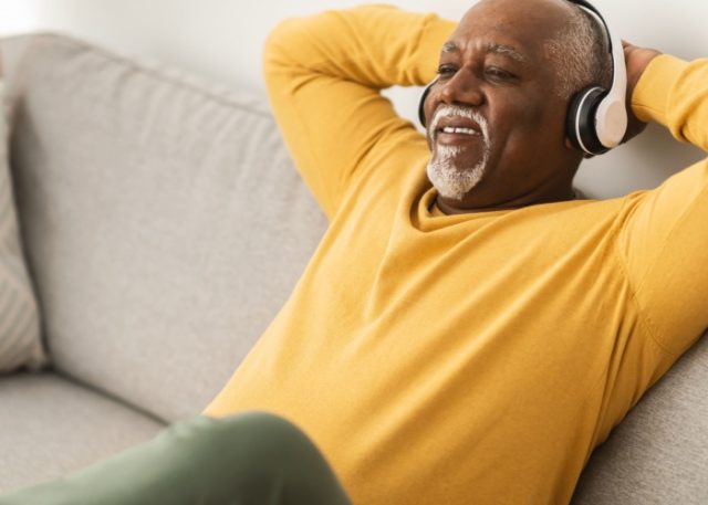 A man relaxing on a sofa with his hands behind his head.