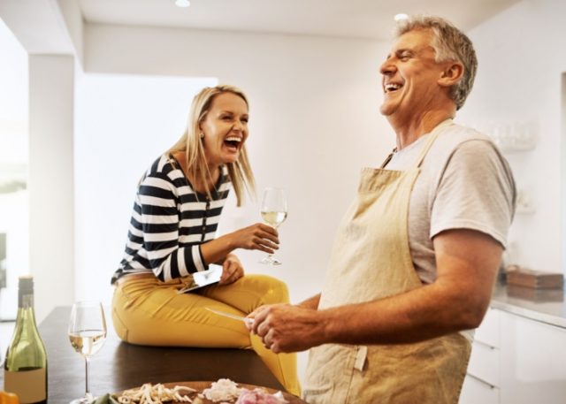 A couple laughing together in their kitchen.