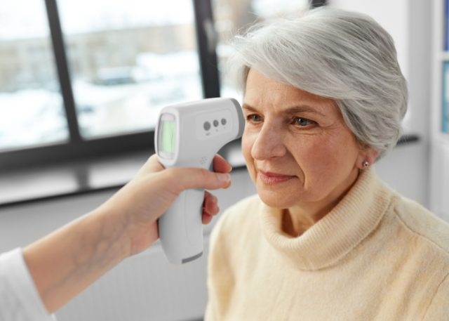 A woman having her temperature taken.