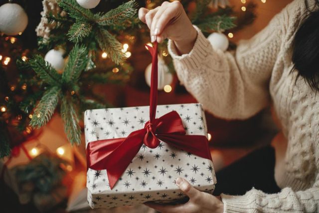 A woman untying a ribbon on a Christmas present.