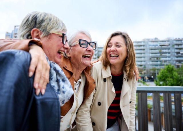 Three women with the around each other laughing.