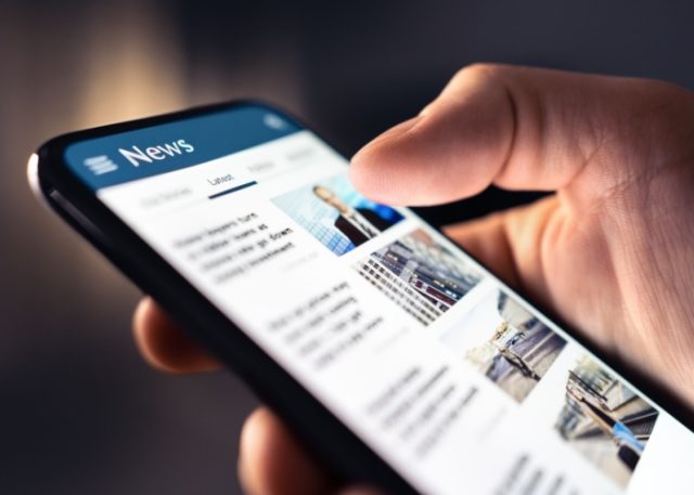 A person looking at a news feed on their phone.