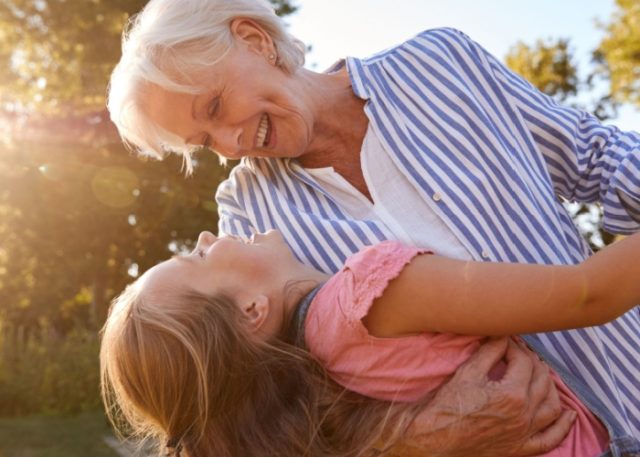 A grandmother playing with her granddaughter outside.
