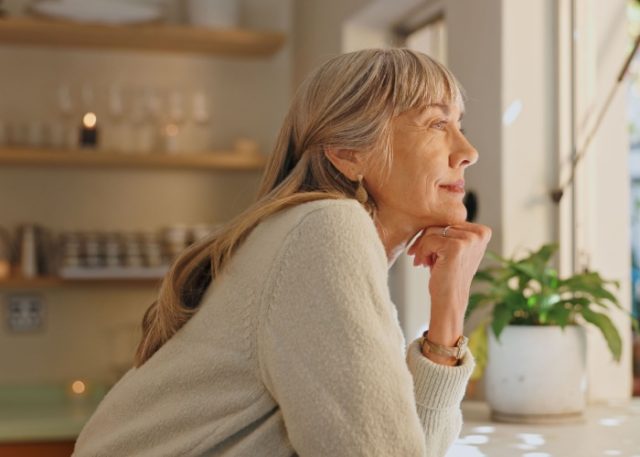 A woman looking out of the window at home.