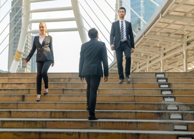 Three office workers crossing on some steps.